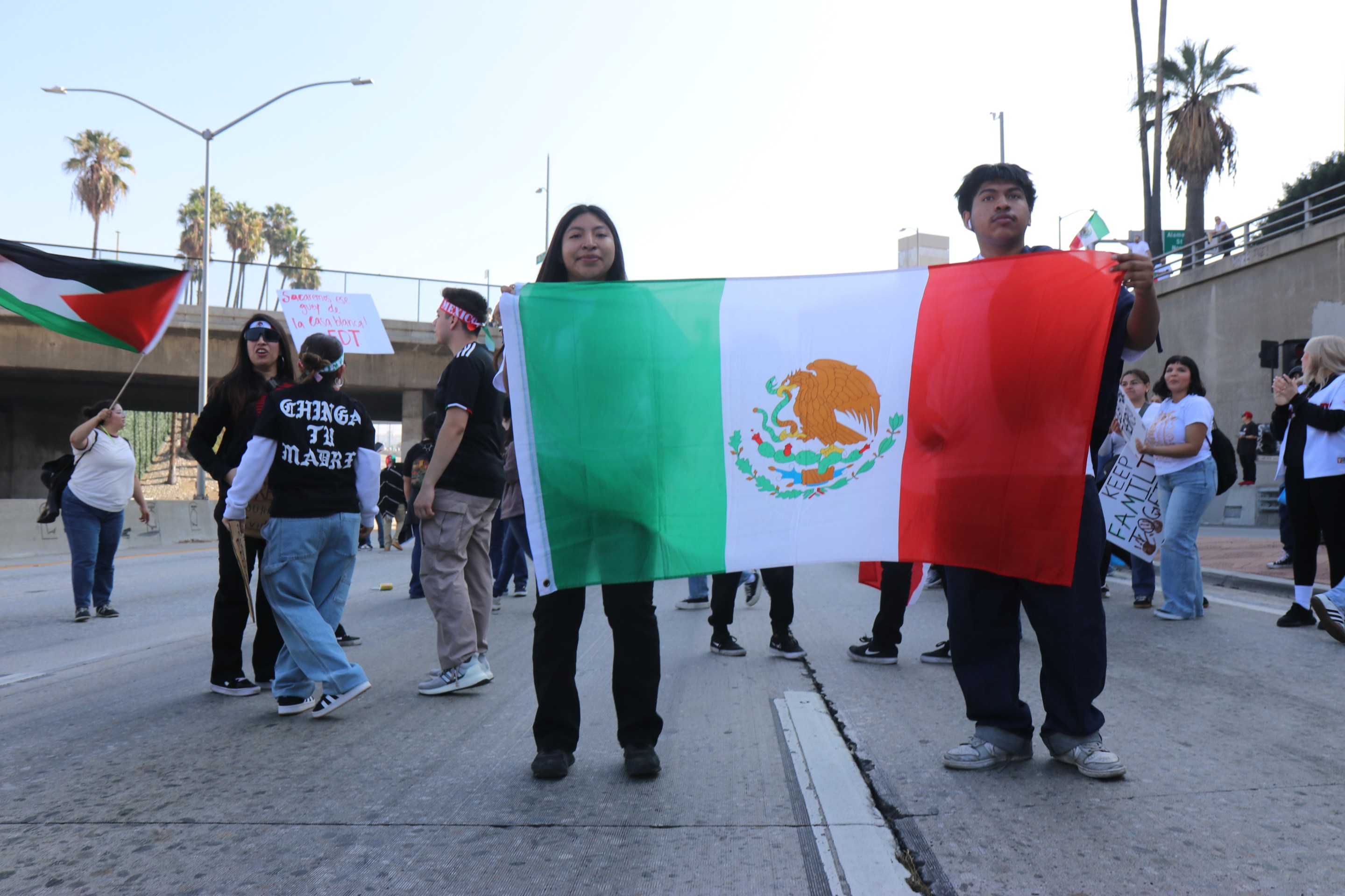 Two protestors holding up a Mexican flag at a protest in downtown Los Angeles.